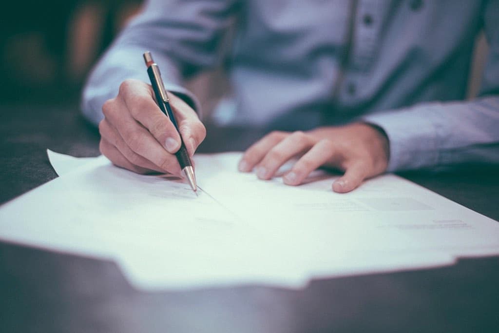 A hand writing notes on a printed report