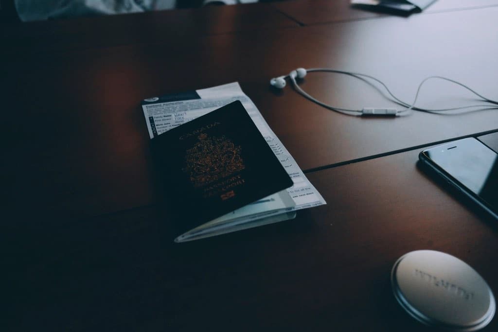 A passport and travel papers on a dark wooden desk