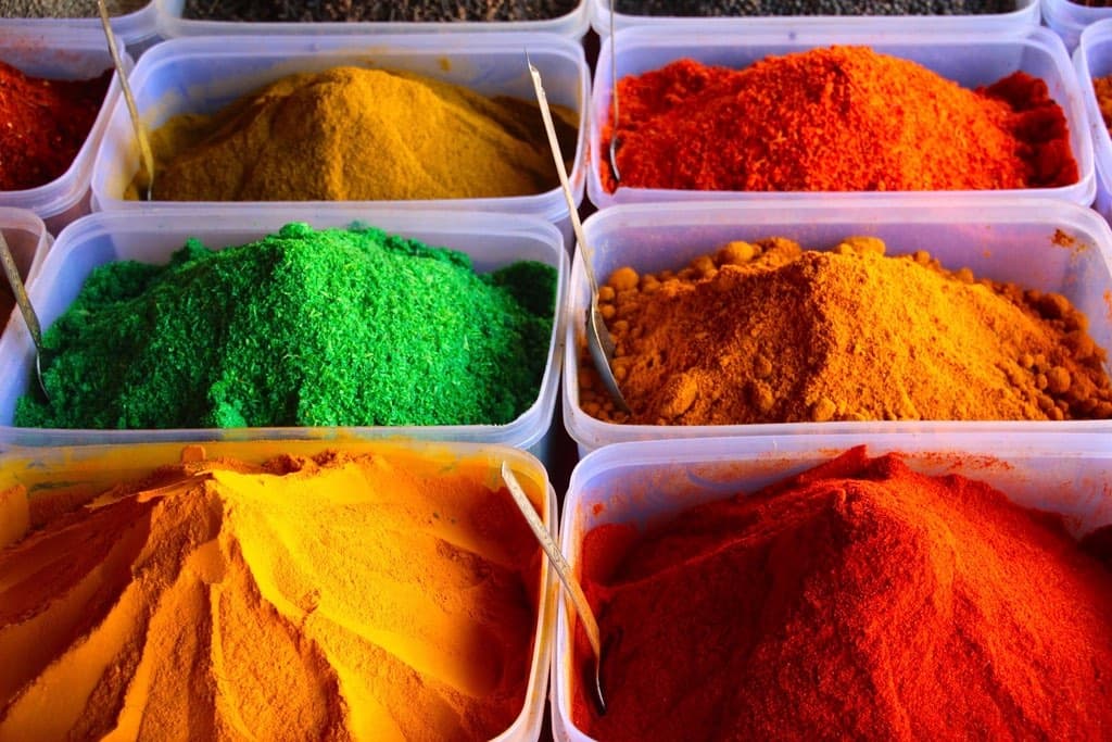 Tubs of brightly coloured ground spices at a market stall